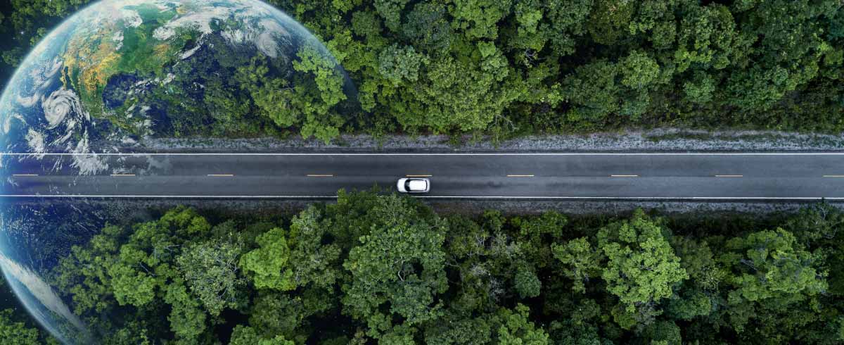 Auto che sta viaggiando su una strada immersa nel verde con il pianeta Terra in dissolvenza