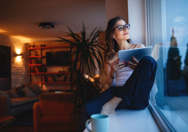 Ragazza con tablet guarda fuori dalla finestra