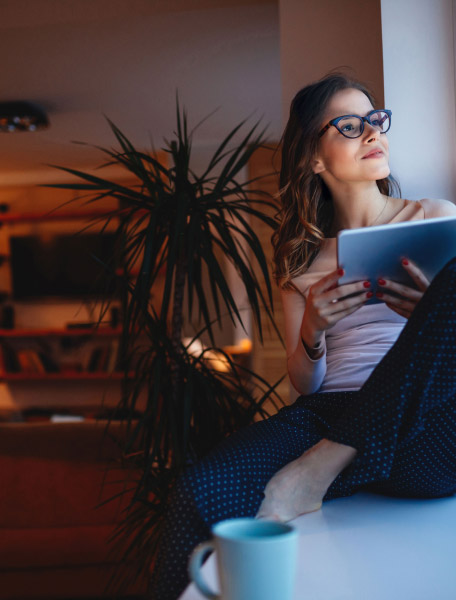 Ragazza con tablet guarda fuori dalla finestra