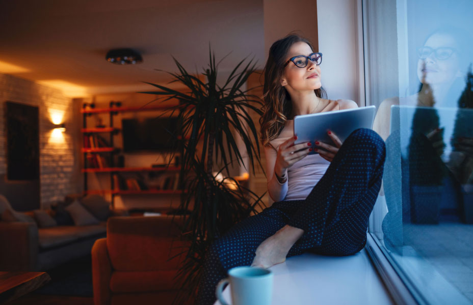 Ragazza con tablet guarda fuori dalla finestra